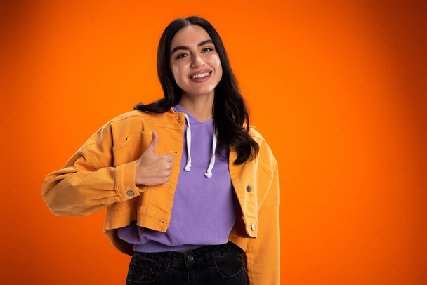 Весела молода жінка, показуючи як знак ізольовано на помаранчевому
 - Фото, зображення