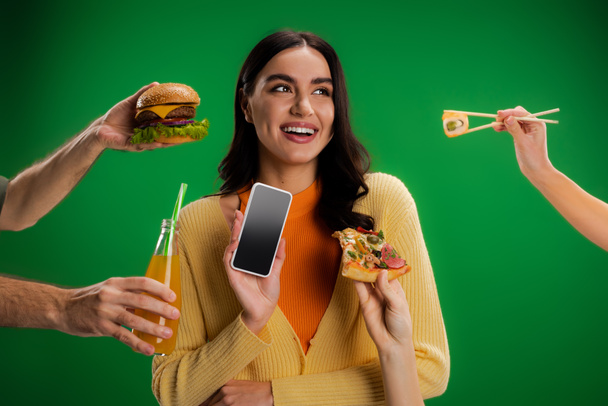 happy woman holding smartphone with blank screen near people with assortment of food isolated on green - Valokuva, kuva