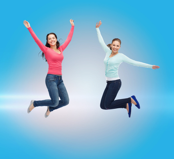 usmívající se mladé ženy skákat do vzduchu - Fotografie, Obrázek