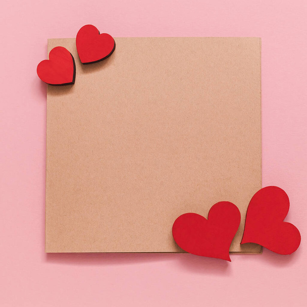 Greeting card with red wooden hearts on a pink background. Valentines Day concept. Top view. Copy space. - Foto, Bild