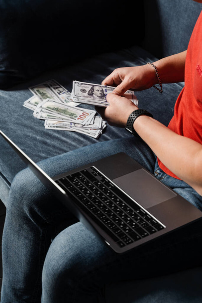 Man with laptop is counting cash dollars and win online bet. Winner in online casino is counting money won - Photo, Image