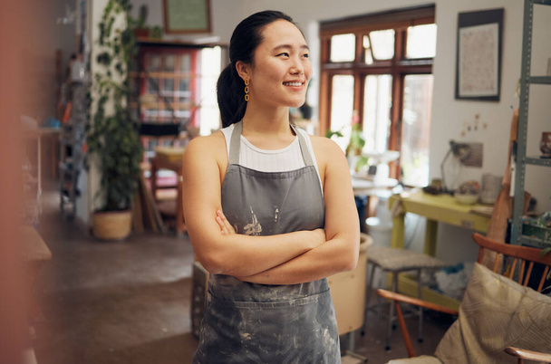 Asian woman, potter and arms crossed in pottery studio, small business or ceramic workshop with ideas, vision or goals. Smile, happy and clay product worker with confidence and creative store design. - Φωτογραφία, εικόνα