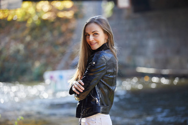 young beautiful girl in black leather jacket on embankment - Φωτογραφία, εικόνα