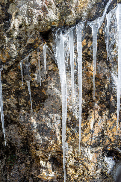 Ice stalactites in the entrance of a cave on a mountain trail in winter. - Fotó, kép