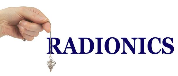 Give Radionics a Try - weibliche Hand, die ein Wünschelruten-Pendel durch das R von RADIONICS baumelt, isoliert auf weißem Hintergrund mit Kopierraum - Foto, Bild