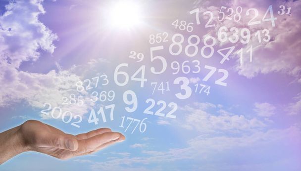 Advies geven over de verborgen betekenis van getallen en numerologie - mannelijke open hand met willekeurige getallen die uit de palm vloeien tegen zonnige blauwe lucht met wolkenachtergrond - Foto, afbeelding