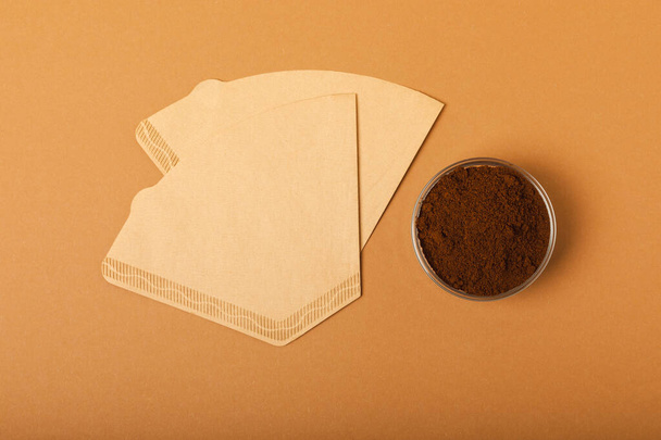 Coffee filter with ground powder on a brown background. fragrant coffee beans for an energizing and invigorating drink. Hand Drip Coffee, Flat Lay of Manual Brew Coffee Tools. - Foto, Bild