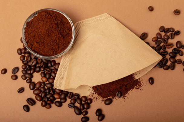 Coffee filter with ground powder on a brown background. fragrant coffee beans for an energizing and invigorating drink. Hand Drip Coffee, Flat Lay of Manual Brew Coffee Tools. - Photo, image