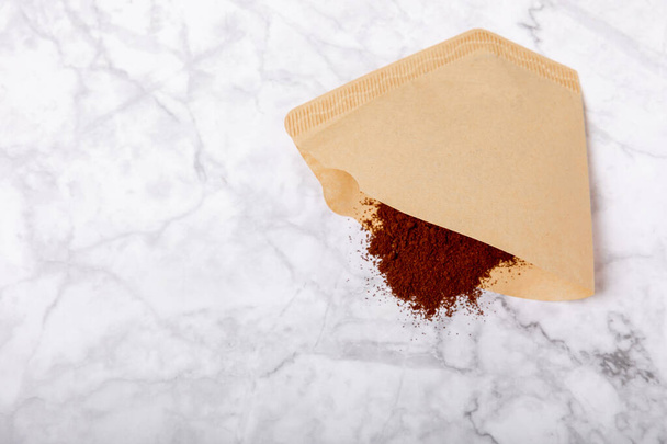 Coffee filter with ground powder on a white marble background. fragrant coffee beans for an energizing and invigorating drink. Hand Drip Coffee, Flat Lay of Manual Brew Coffee Tools - Fotografie, Obrázek