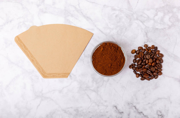 Coffee filter with ground powder on a white marble background. fragrant coffee beans for an energizing and invigorating drink. Hand Drip Coffee, Flat Lay of Manual Brew Coffee Tools - Foto, Bild