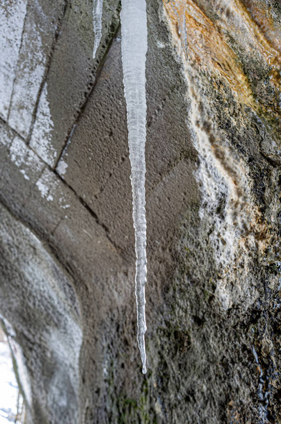 Ледовые сталактиты у входа в пещеру на горной тропе зимой. - Фото, изображение