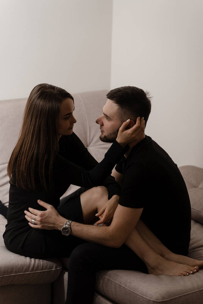 Love story of a couple spending time in cozy room at home. Relationships, feelings and tenderness in the family of men and girl. Couple in love hugging and kissing on couch at home - Fotoğraf, Görsel