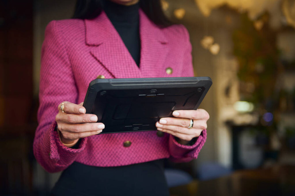 Details on digital tablet in the hands of a restaurateur, businesswoman in bright purple casual wear, executive director or successful manager, CEO against blurred background of a restaurant interior - Foto, Imagem