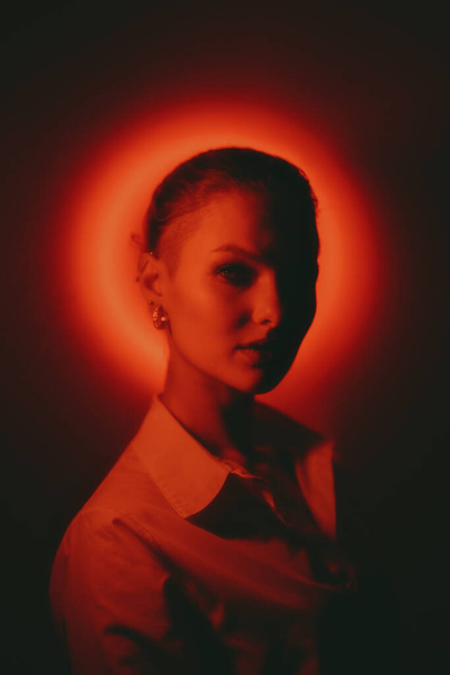 Woman portrait with glowing neon red circle on dark background looking to camera - Fotoğraf, Görsel