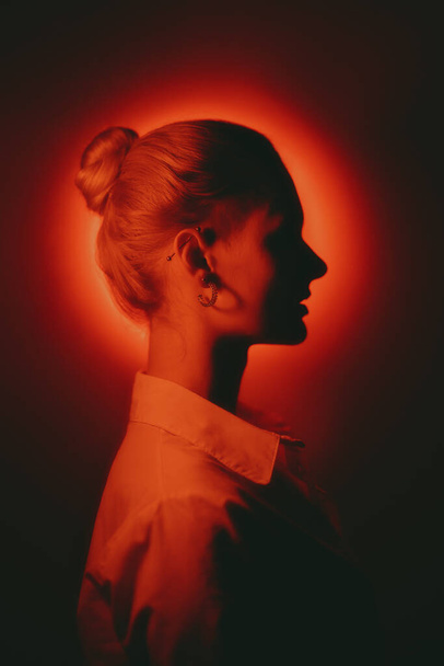 Woman profile portrait with glowing neon red circle on dark background - Fotografie, Obrázek