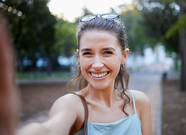 Selfie, young woman and casual in park, walking and smile for fun, balance and happiness. Portrait, female and lady with joy, summer and chilling outdoor, cheerful and freedom on break and weekend. - Photo, image