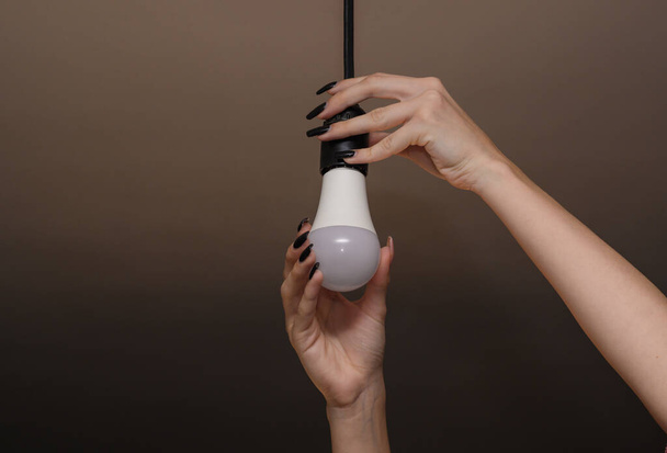 Women's hands screw in a light bulb. led lamp - Foto, imagen