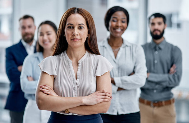 Never underestimate the power of a dedicated team. Portrait of a businesswoman standing in an office with her colleagues in the background - Photo, image