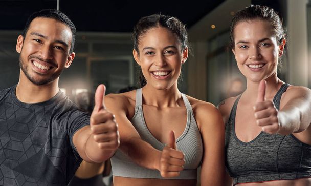 We can back that. Cropped portrait of three young athletes giving thumbs up while standing in the gym - Foto, Bild