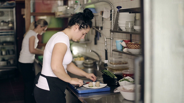 Étterem konyha nő előkészítése hal ételeket a vendégek. Közepes lövés. - Felvétel, videó