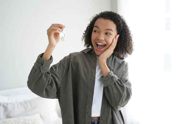Excited happy mixed race teen girl tenant showing keys to new home. Modern joyful young lady delighted with moving and purchasing own apartment. Real estate rental service advertising. - Foto, Imagem