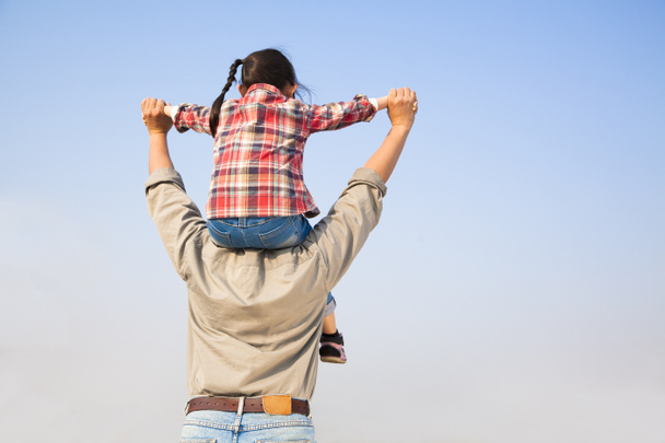Vader die zijn dochter op schouders met blauwe hemel CHTERGRO - Foto, afbeelding