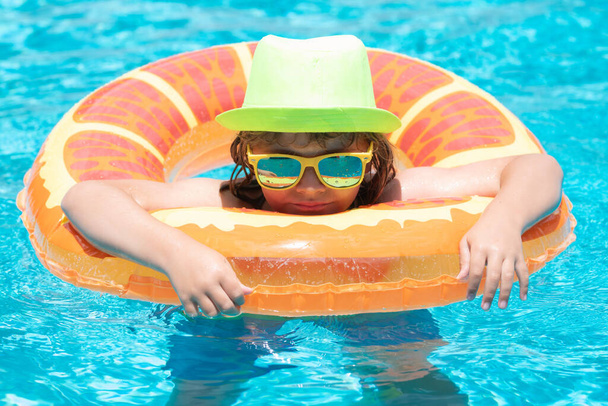 Child boy splashing in swimming pool. Swim water sport activity on summer vacation with children - 写真・画像