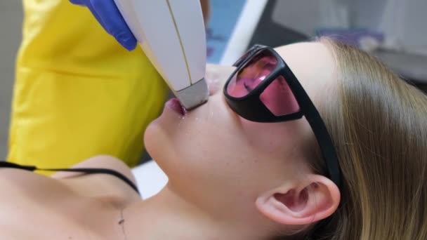 A professional beautician performs laser epilation to remove excess hair on a young patient. Body care in a beauty salon - Materiał filmowy, wideo