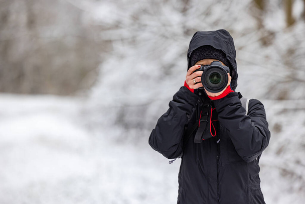 φωτογράφος γυναίκα με επαγγελματική φωτογραφική μηχανή γυρίσματα σε εξωτερικούς χώρους το χειμώνα - Φωτογραφία, εικόνα