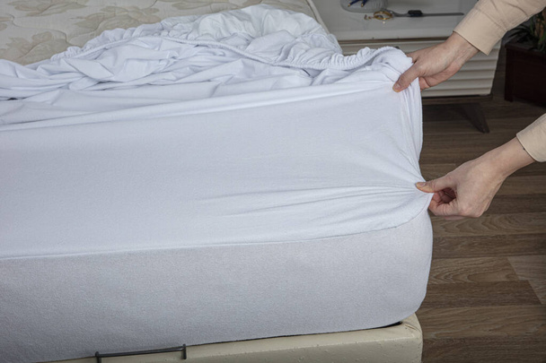 Corner of the sheet with sewn-in elastic band for a good fit on the mattress and a comfortable sleep. White fabric for mockup overlay design. Home textiles for the bedroom. Bedspread mattress. - Foto, afbeelding