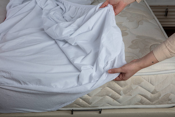 Corner of the sheet with sewn-in elastic band for a good fit on the mattress and a comfortable sleep. White fabric for mockup overlay design. Home textiles for the bedroom. Bedspread mattress. - Φωτογραφία, εικόνα