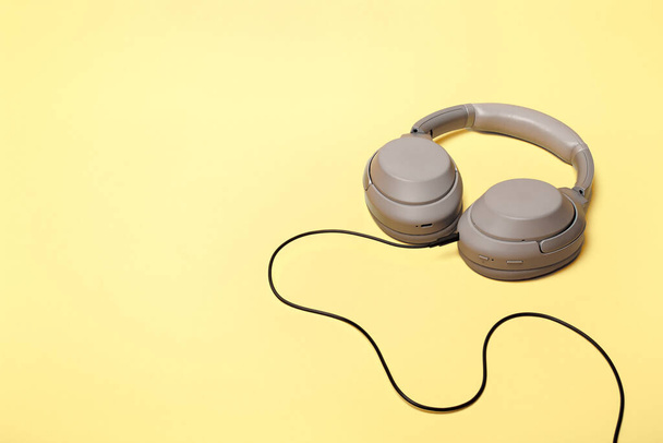 Light gray wireless on-ear headphones with the ability to connect via wire on a sand-colored background. Headphones for playing games or listening to music. Noise canceling headphones. Top view. Copy space - Photo, Image