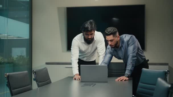 Two Arabian Indian workers managers partners businessmen in office discuss business problem with laptop analyze online result African American woman leader walk in boardroom help with computer work - Imágenes, Vídeo