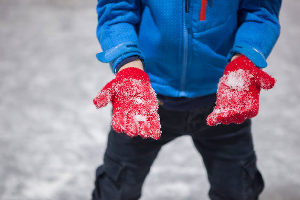 Child boy show his gloves full of ice. Recreational ice rink concept - Foto, imagen