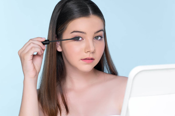 Closeup portrait of young charming applying makeup eyeshadow on her face with brush, mascara with flawless smooth skin for beauty concept. - Foto, immagini