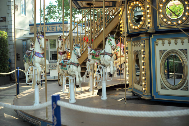 Motioned blurred picture of horse of the carousel with defocused horses and bokeh lights in background. - Fotó, kép