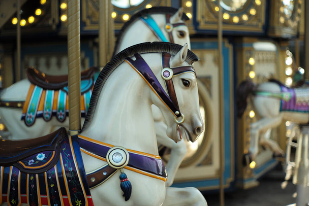 Motioned blurred picture of horse of the carousel with defocused horses and bokeh lights in background. - Fotó, kép