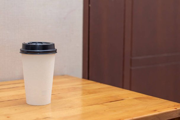 White blank image of a paper cup on the top of a table with blurred out background, on the top of a table - Foto, Imagem
