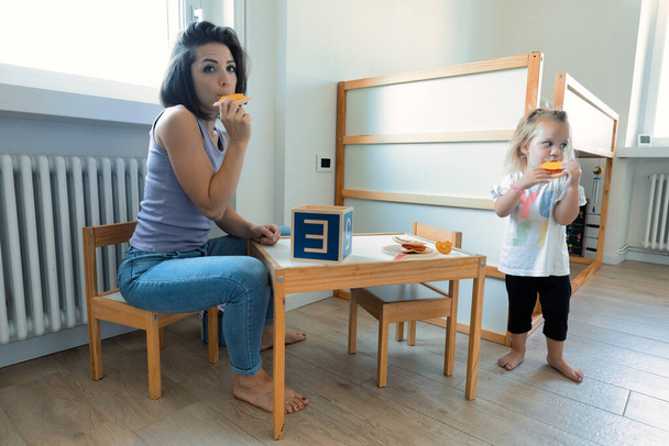 mother and daughter play with wooden cubes, with letters on the faces and able to hold smaller ones; the room is bright and clear - Foto, Bild