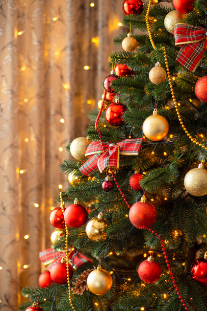 装飾されたクリスマスツリーのクローズアップ垂直ショット。黄金と赤のボール、ライト、お正月を祝うにはモミの木 - 写真・画像