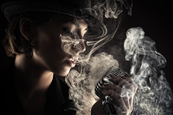 Singer woman with retro microphone in smoke - Фото, изображение