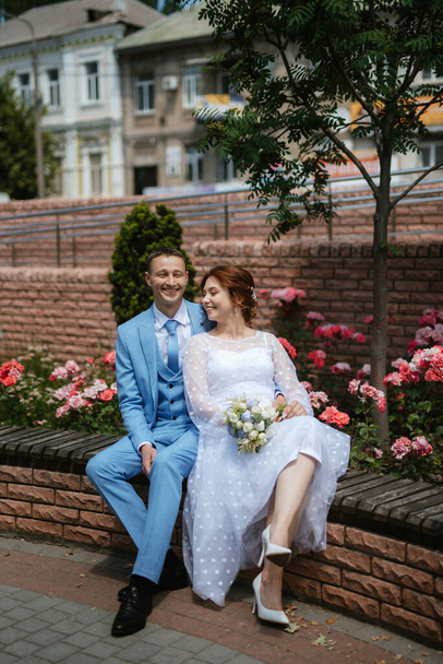 bride in a light wedding dress with a bouquet next to the groom in a blue suit - 写真・画像