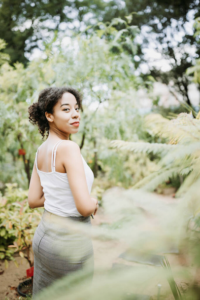 Mujer joven afroamericana multirracial en camiseta blanca en parque o calle al aire libre. Primavera o verano - Foto, imagen