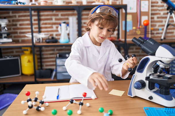 Adorável caucasiano menino estudante segurando moléculas na sala de aula - Foto, Imagem