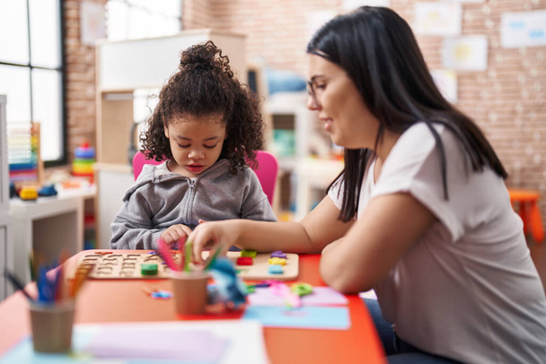 Учитель и ребенок играют с математикой головоломка игра сидит на столе в детском саду - Фото, изображение