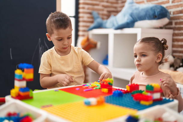 Two kids playing with construction blocks sitting on table at kindergarten - Foto, Imagen