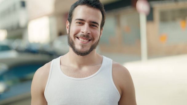 Joven hombre hispano sonriendo confiado de pie en la calle - Foto, Imagen