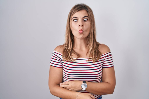 Young hispanic woman standing over isolated background making fish face with lips, crazy and comical gesture. funny expression.  - Photo, Image