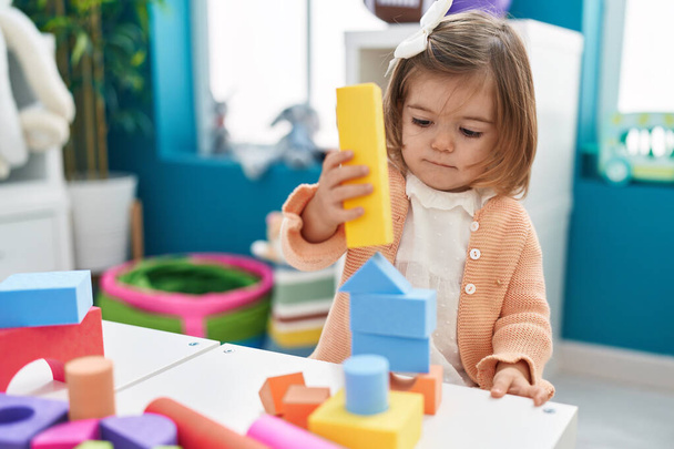 Чарівний блондинка малюк грає з будівельними блоками, що стоять в дитячому саду
 - Фото, зображення