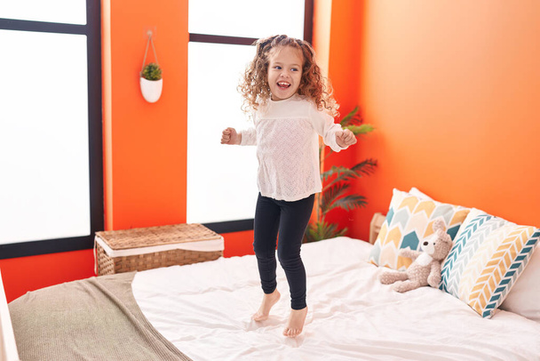 Adorable blonde toddler smiling confident jumping on bed at bedroom - Valokuva, kuva